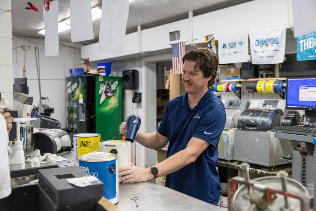 Duval Paint employee,. Derek, helps a client with a paint can